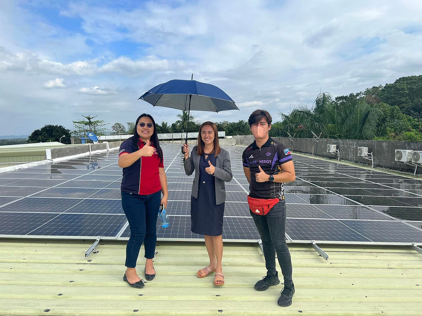 Three people on a rooftop beside a completed solar array, one wearing a Gleenergy shirt